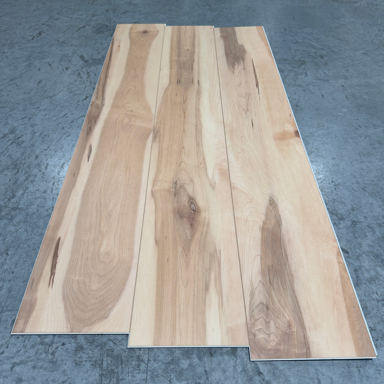 Toucan SPC Flooring 510 - 6MM - Three planks showing light cream-tan hickory grain with bold dark mineral streaking and large knots